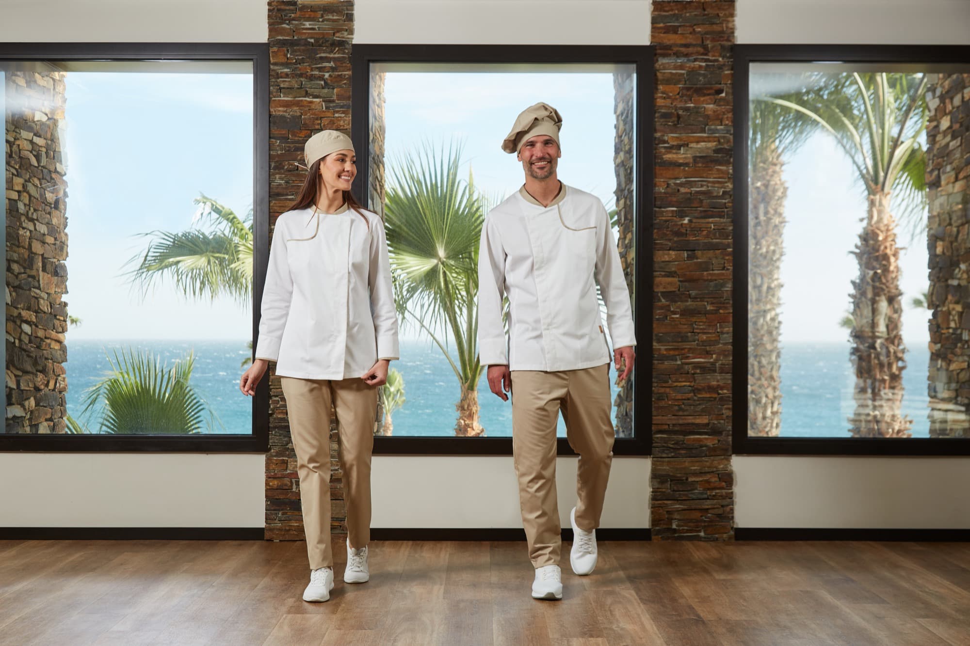 Two cooks in Horeca jackets and caps in a sea-view dining room